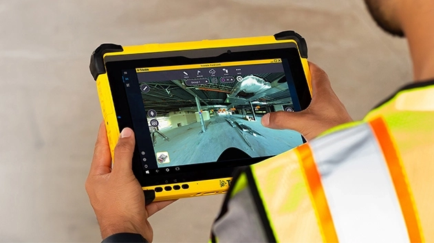 Man in reflective vest using Trimble FieldLink software on tablet in construction site