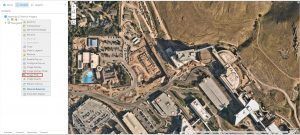 Aerial view of a developed area with buildings, roads, a swimming pool, and a construction site.